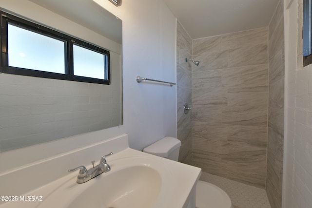 full bathroom featuring toilet, a tile shower, and vanity