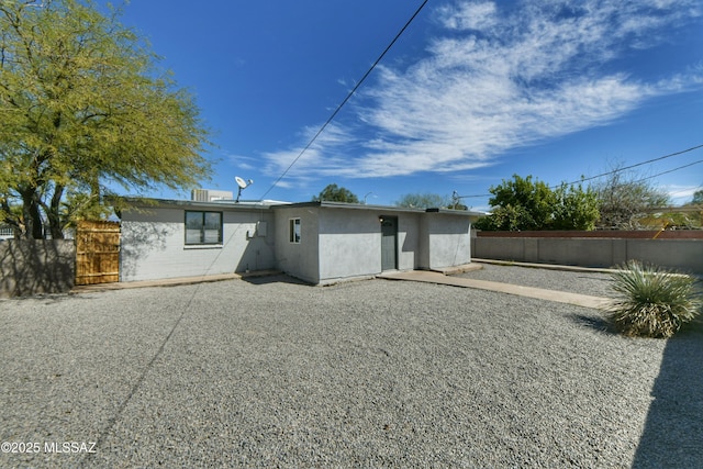 rear view of property featuring stucco siding, fence, and a patio