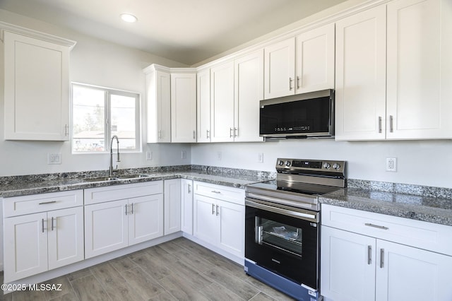 kitchen with light hardwood / wood-style flooring, sink, white cabinetry, stainless steel electric stove, and dark stone countertops