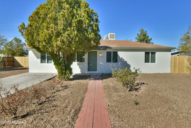 ranch-style home featuring a shingled roof, fence, and stucco siding