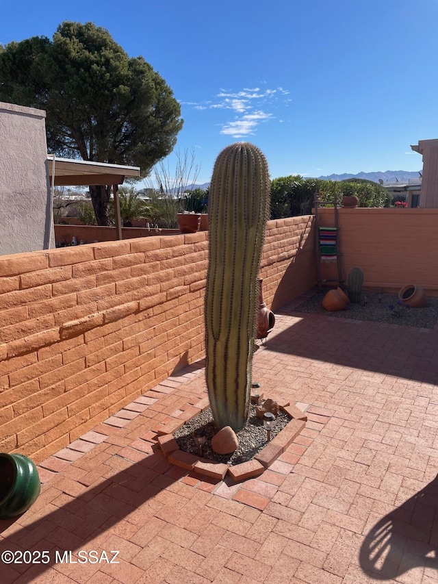 view of patio with fence and a mountain view