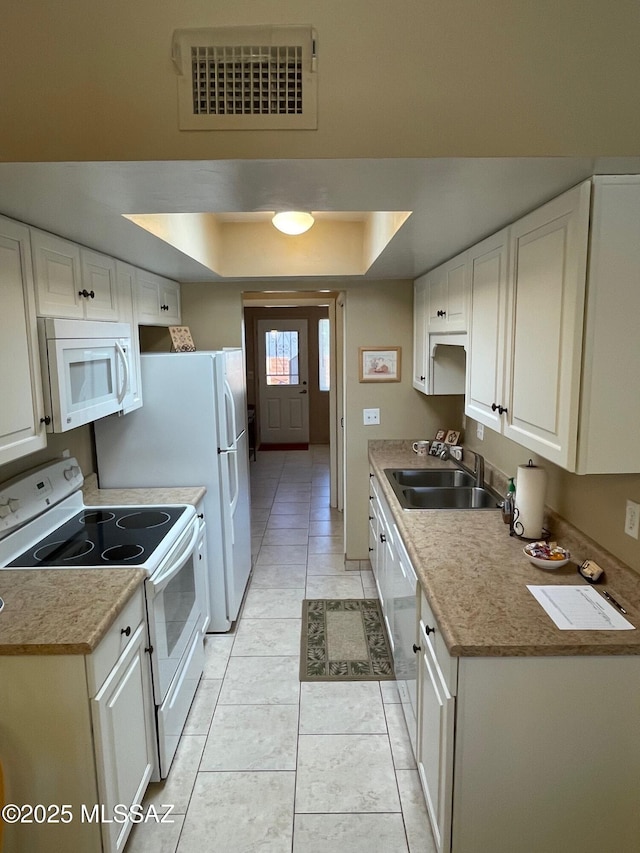 kitchen featuring white appliances, white cabinetry, visible vents, and a sink