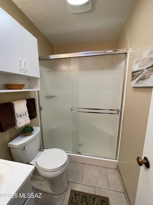 bathroom featuring toilet, a stall shower, tile patterned flooring, and vanity