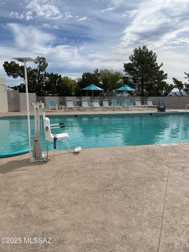 pool with a patio area and fence