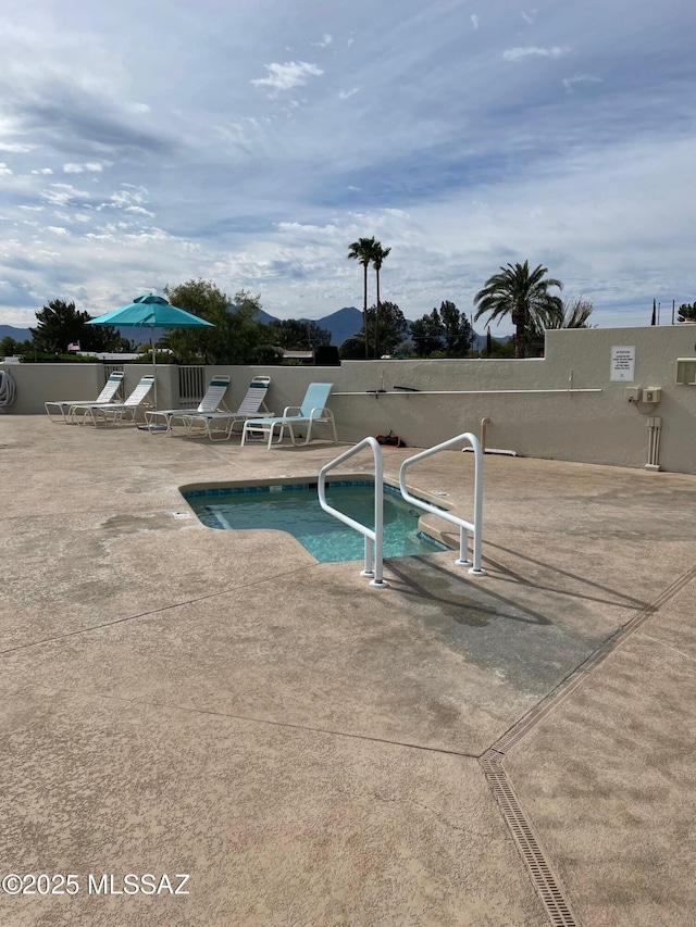 pool with a patio, fence, and a mountain view