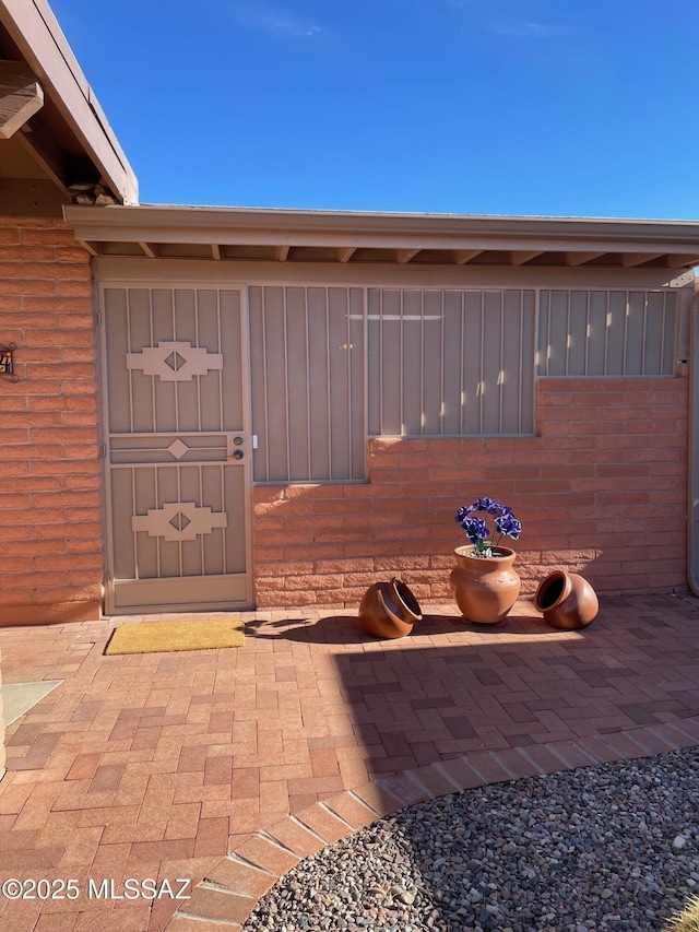 property entrance featuring board and batten siding, brick siding, and a patio