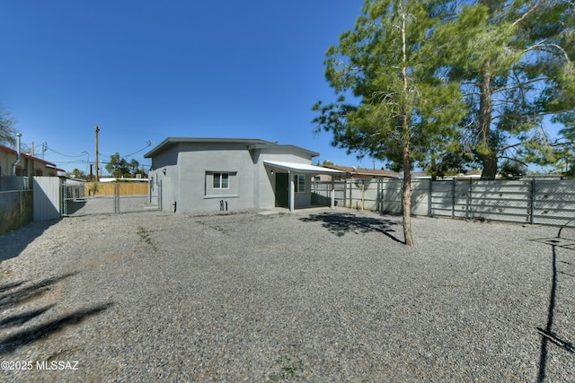 back of house with stucco siding and a fenced backyard