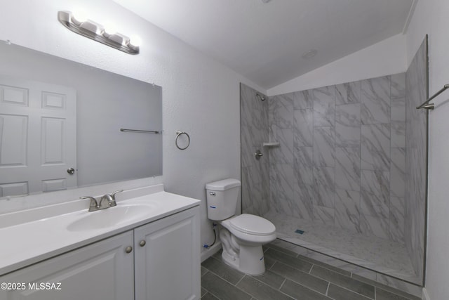 full bathroom with vanity, lofted ceiling, toilet, and a tile shower