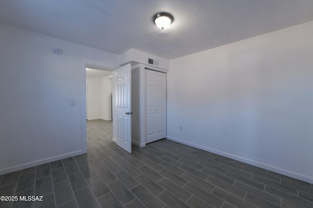 empty room with visible vents, dark wood-type flooring, and baseboards