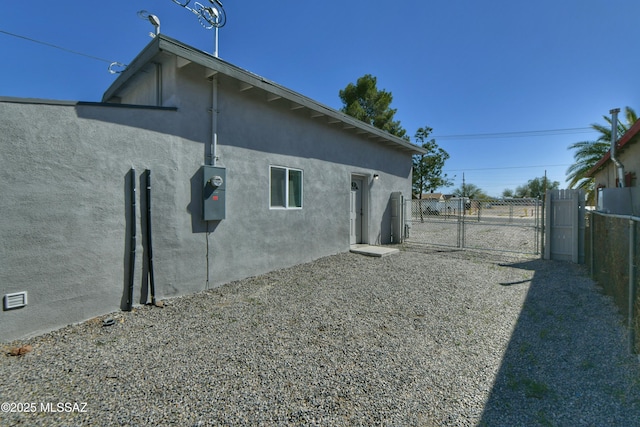 view of property exterior with a gate, fence, and stucco siding