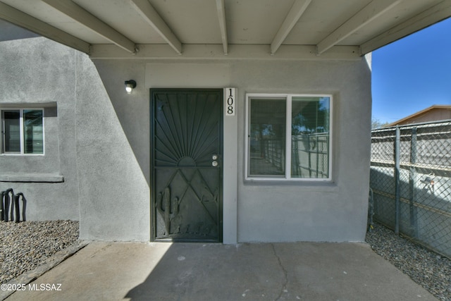 property entrance featuring fence and stucco siding