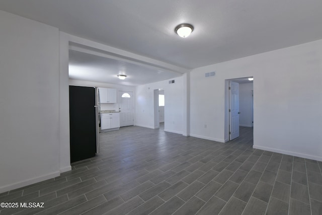 unfurnished living room featuring visible vents and baseboards