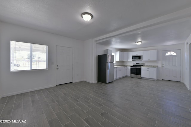 kitchen featuring dark wood-style floors, baseboards, white cabinets, appliances with stainless steel finishes, and open floor plan