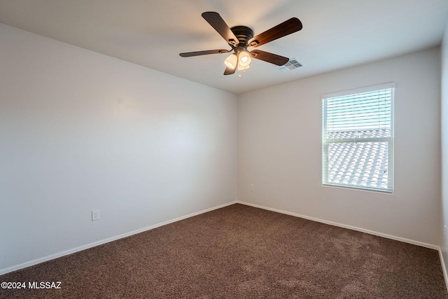 empty room featuring ceiling fan and dark colored carpet