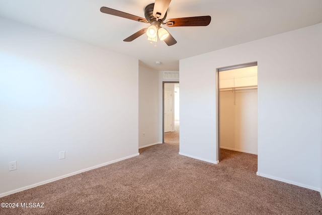 unfurnished bedroom with ceiling fan, carpet floors, a walk in closet, and a closet