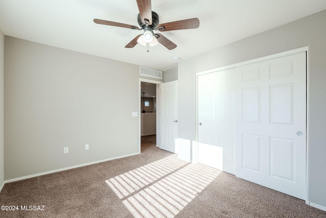 unfurnished bedroom with ceiling fan, carpet flooring, and a closet