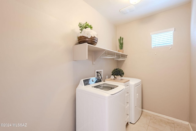 clothes washing area with washing machine and dryer and light tile patterned floors