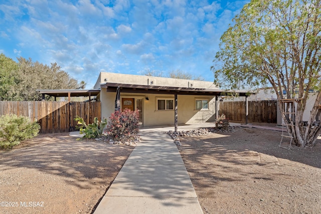 rear view of property featuring fence and stucco siding