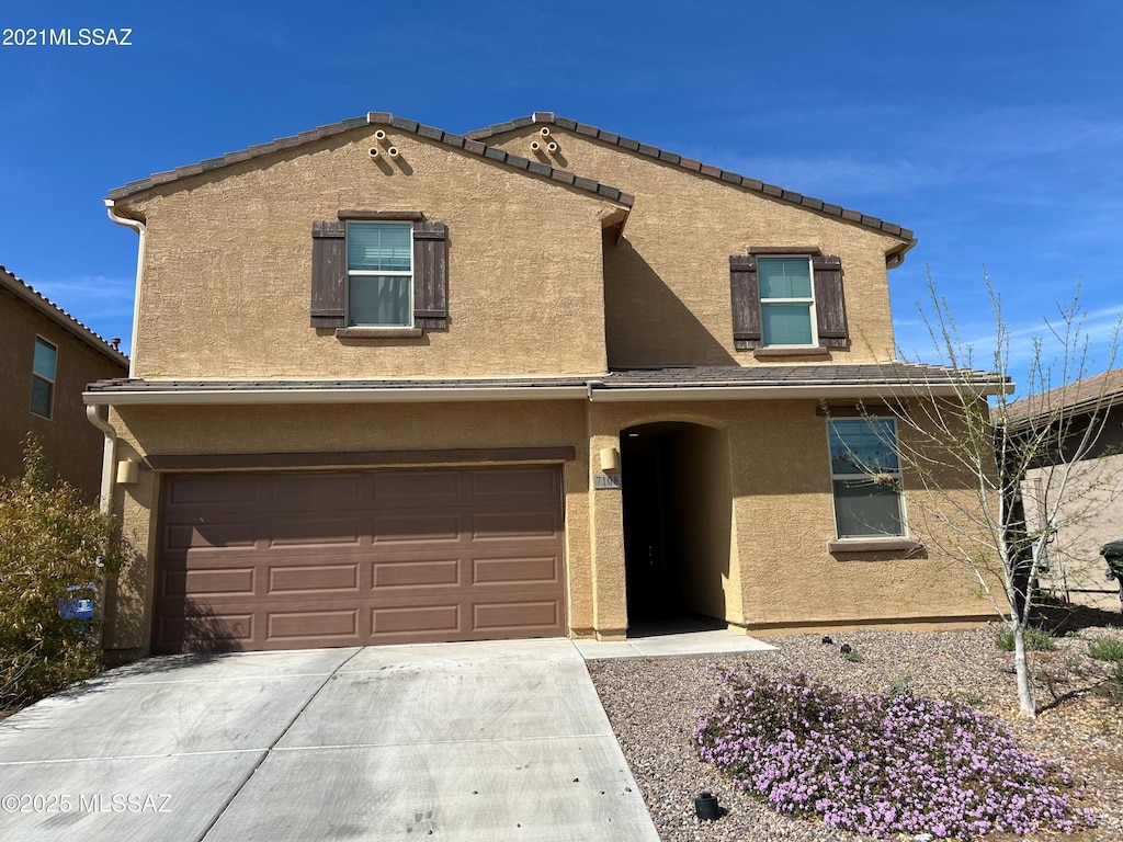 traditional-style home with an attached garage, concrete driveway, and stucco siding