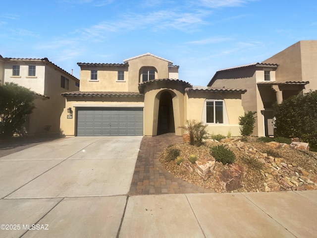 mediterranean / spanish home featuring driveway, a tile roof, a garage, and stucco siding