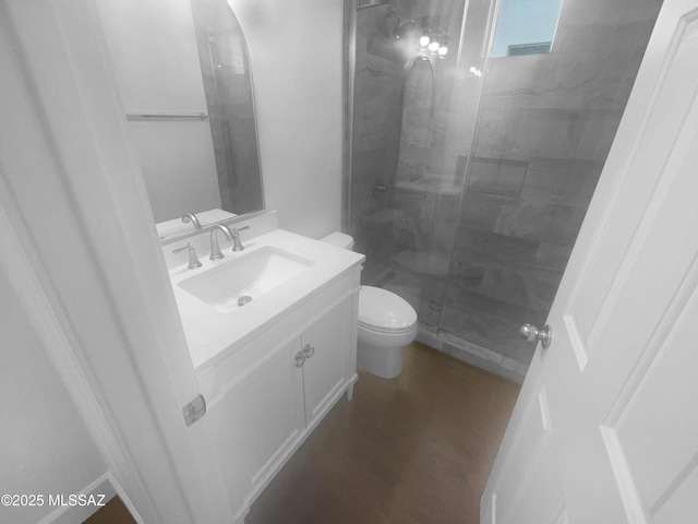 bathroom with a shower stall, vanity, toilet, and wood finished floors