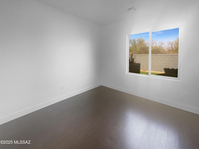 spare room with visible vents, baseboards, and wood finished floors