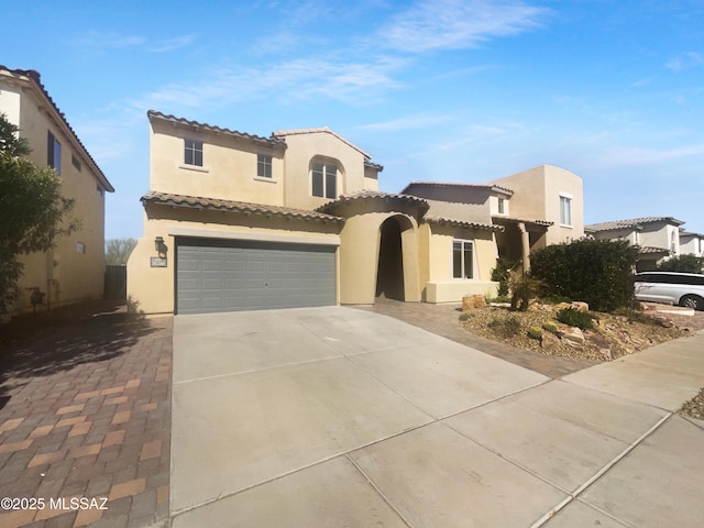 mediterranean / spanish house with an attached garage, concrete driveway, and stucco siding