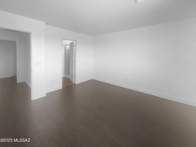 unfurnished room featuring baseboards and dark wood-type flooring