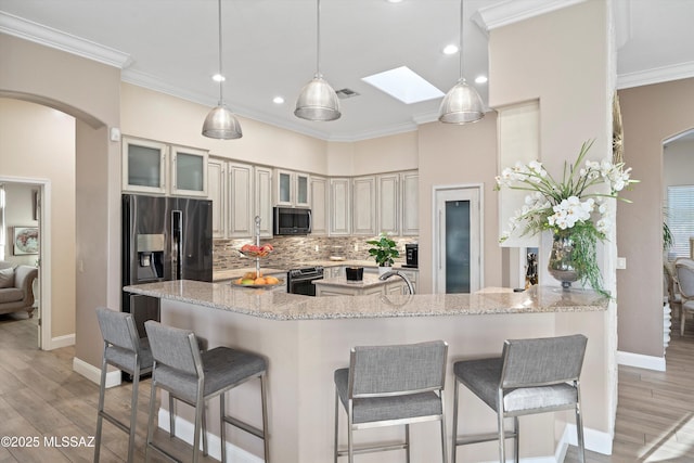 kitchen featuring decorative backsplash, a kitchen breakfast bar, light wood-style floors, and appliances with stainless steel finishes