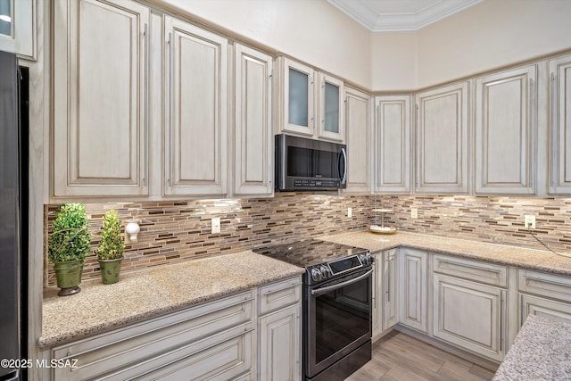 kitchen featuring decorative backsplash, stainless steel appliances, light wood-style floors, crown molding, and glass insert cabinets