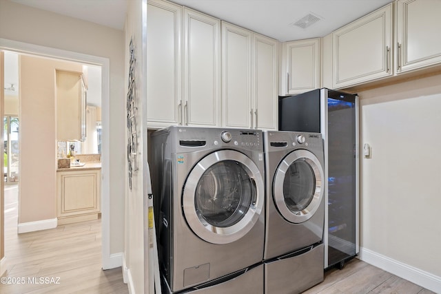 laundry area featuring visible vents, baseboards, light wood-style flooring, and washer and clothes dryer