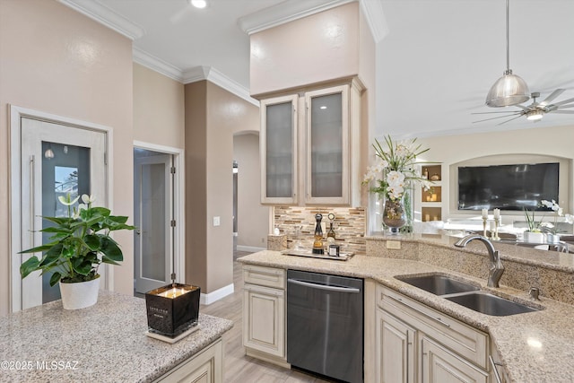 kitchen with cream cabinetry, light stone counters, stainless steel dishwasher, a sink, and arched walkways