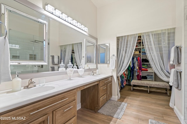 full bathroom with double vanity, a spacious closet, wood finished floors, and a sink