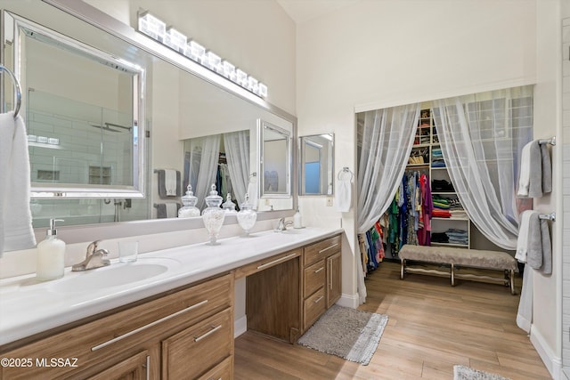 full bath with a spacious closet, wood finished floors, a sink, and double vanity