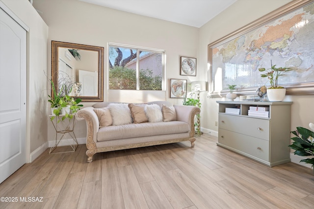 sitting room with plenty of natural light, baseboards, and light wood-type flooring