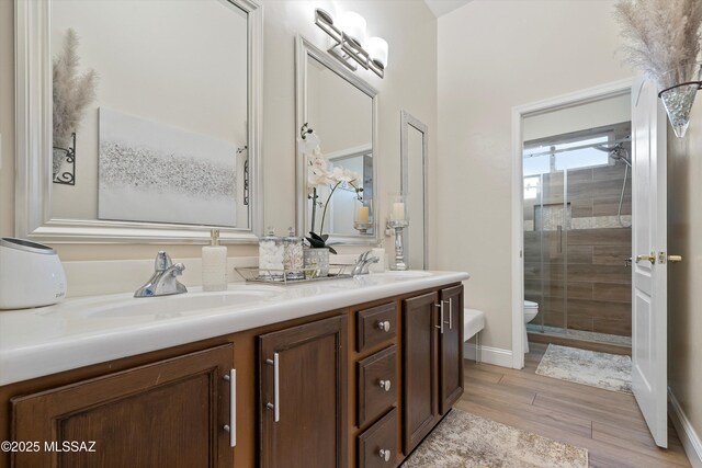 full bathroom with toilet, a sink, double vanity, and tiled shower
