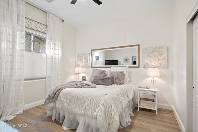 bedroom with visible vents, a ceiling fan, baseboards, and wood finished floors