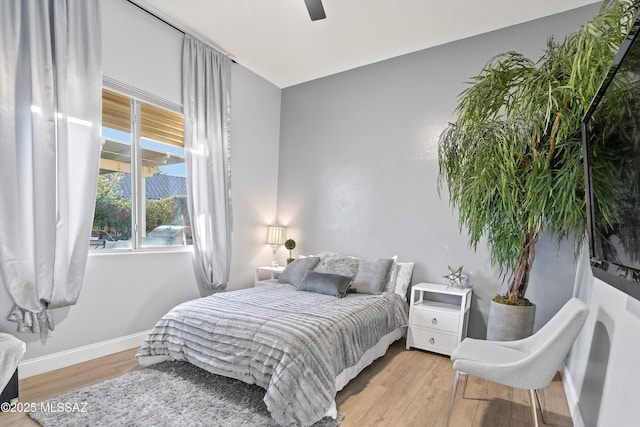 bedroom with light wood finished floors, a ceiling fan, and baseboards