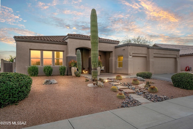 view of front facade with an attached garage, a tiled roof, and stucco siding