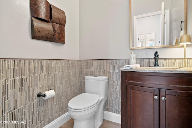 bathroom with a wainscoted wall, vanity, and toilet