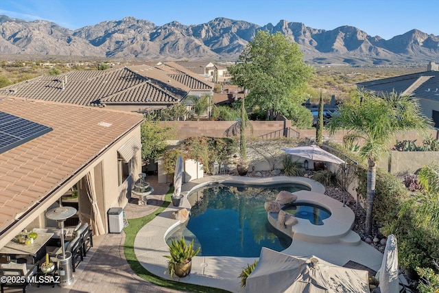 view of swimming pool with central air condition unit, a mountain view, a pool with connected hot tub, and a fenced backyard