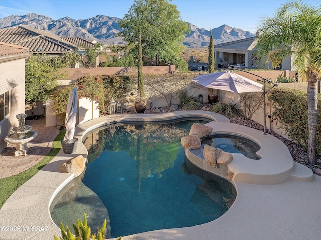 pool with a patio, a fenced backyard, an in ground hot tub, and a mountain view