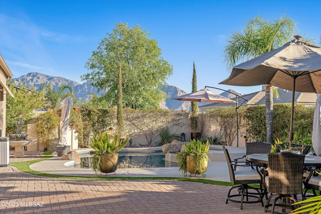 view of patio / terrace with outdoor dining space, a fenced in pool, and a mountain view