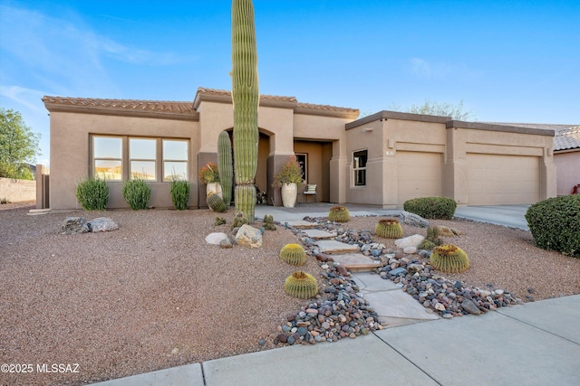 adobe home featuring an attached garage, a tile roof, driveway, and stucco siding