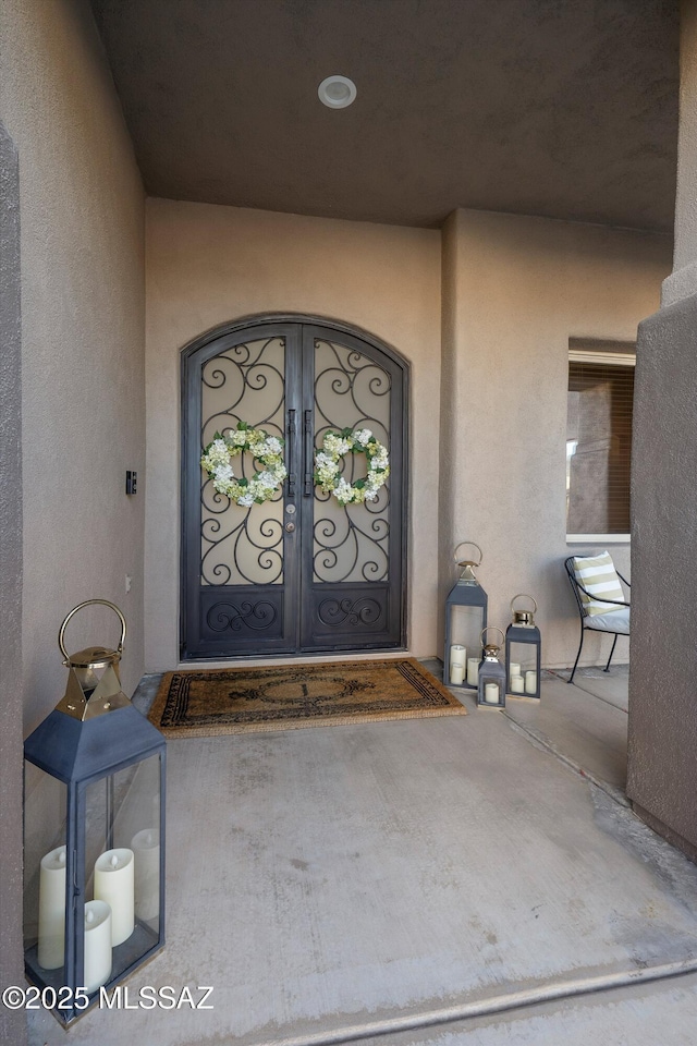 entrance to property featuring stucco siding and french doors