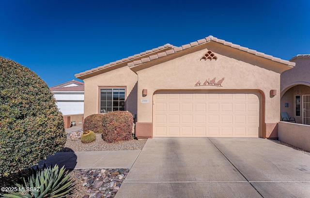 mediterranean / spanish home featuring a garage, driveway, a tiled roof, and stucco siding