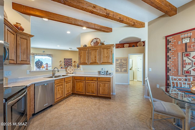 kitchen featuring light countertops, appliances with stainless steel finishes, brown cabinetry, and a sink