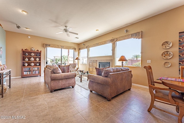 living area featuring visible vents, a tile fireplace, a ceiling fan, and baseboards