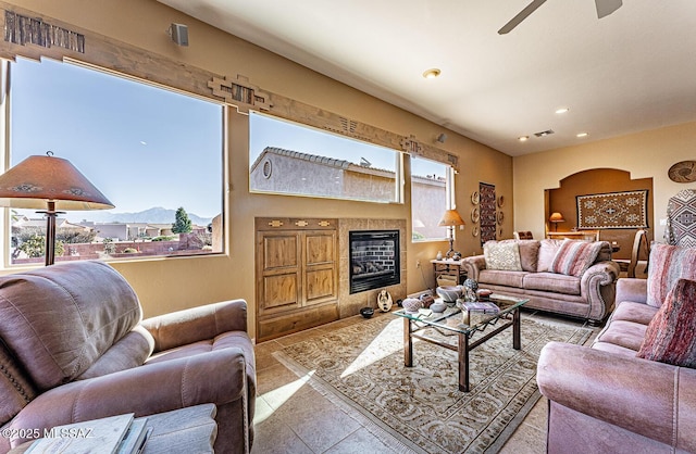 living room featuring a tiled fireplace, a mountain view, a wealth of natural light, and light tile patterned flooring