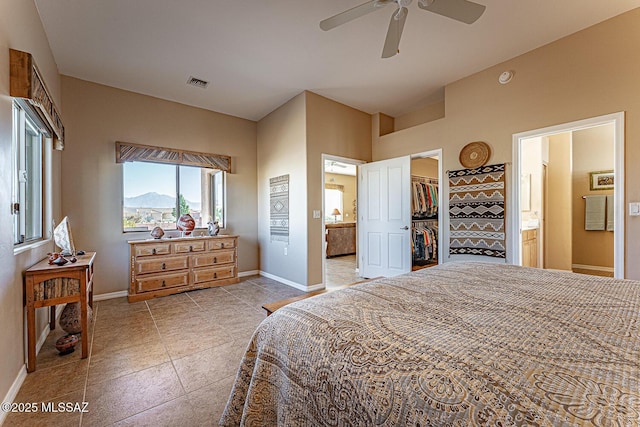 bedroom featuring a walk in closet, visible vents, a mountain view, ensuite bath, and baseboards